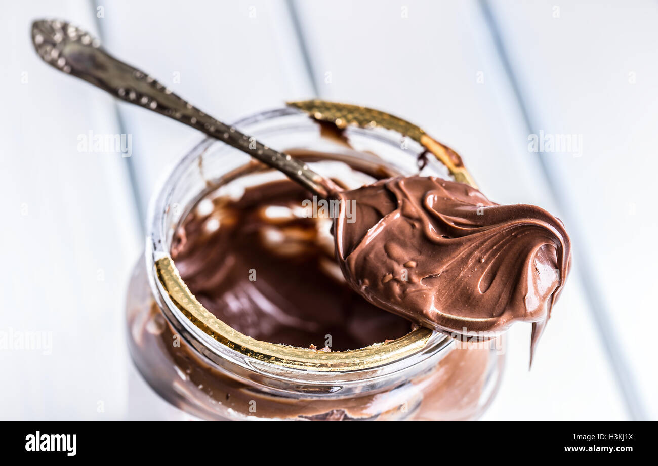 Chocolate propagación en la cuchara. Un tarro de chocolate con avellanas propagación. Foto de stock