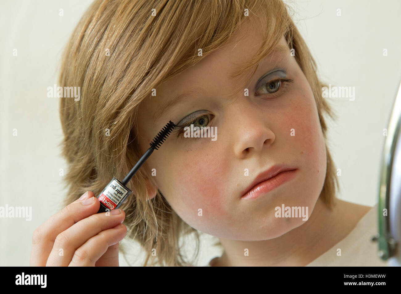 Joven poniendo maquillaje simulando ser una niña Foto de stock