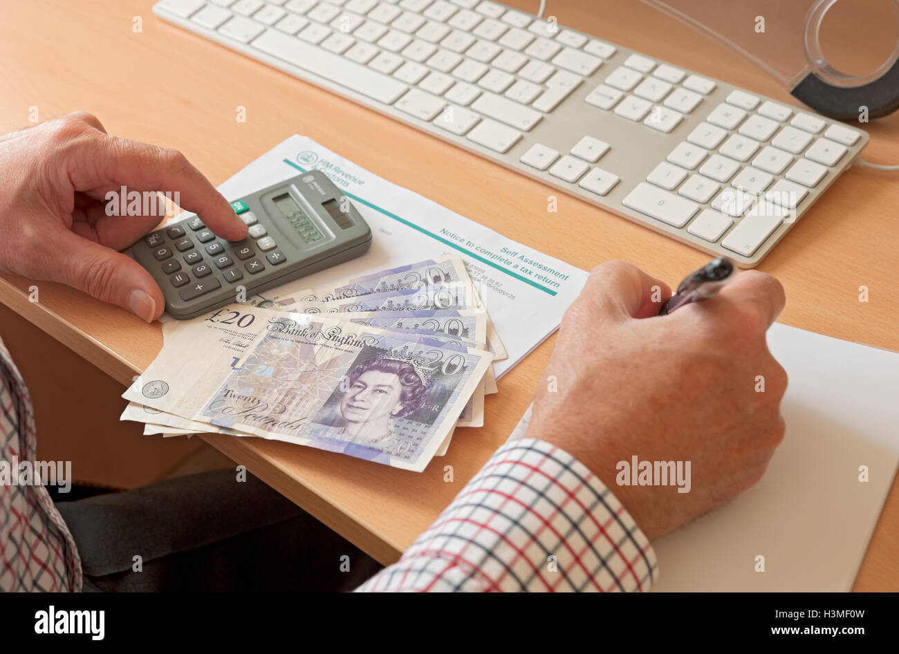 Primer plano de hombre de negocios persona completando HMRC auto evaluación  de impuestos calculadora y dinero Inglaterra Reino Unido GB Gran Bretaña  Fotografía de stock - Alamy