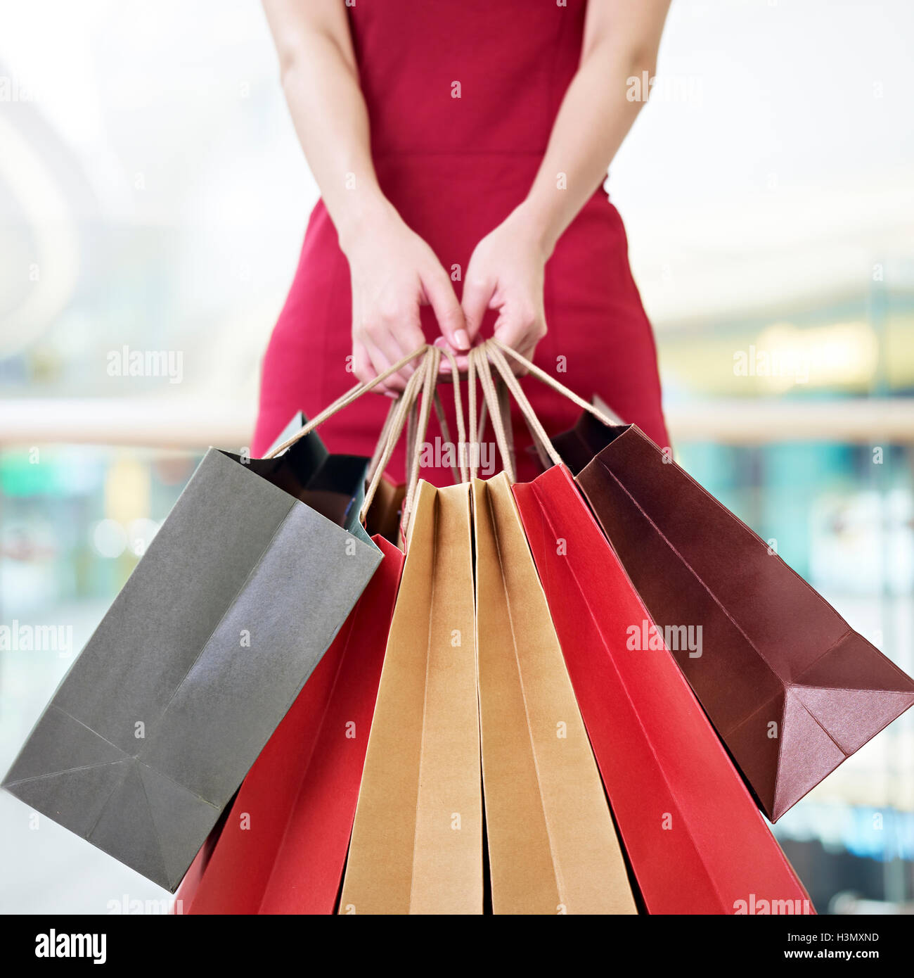 Mujer joven shopper femenino de pie con coloridas bolsas de papel en las manos en un centro comercial o tienda departamental, centrarse en las bolsas de papel Foto de stock