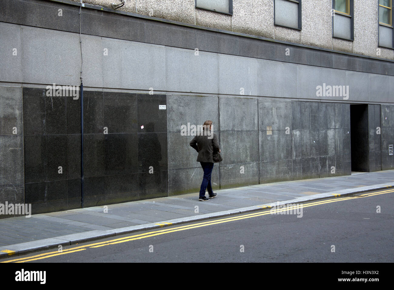 Glasgow escenas callejeras hombre caminando solo fondo de granito gris Foto de stock