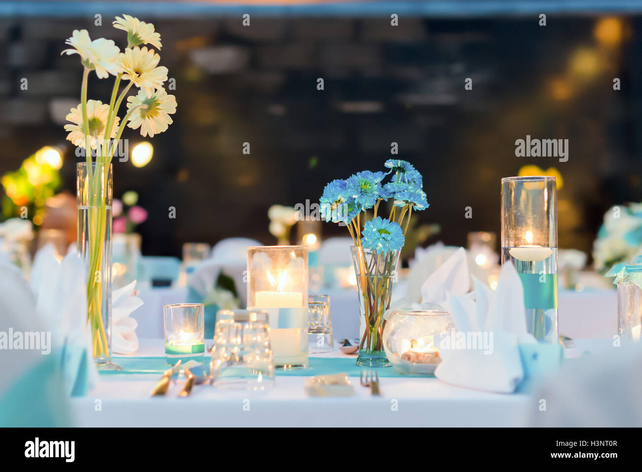 Cena romántica setup, tema blanco y azul decorado con luz de velas, linternas y flores. El enfoque selectivo. Foto de stock