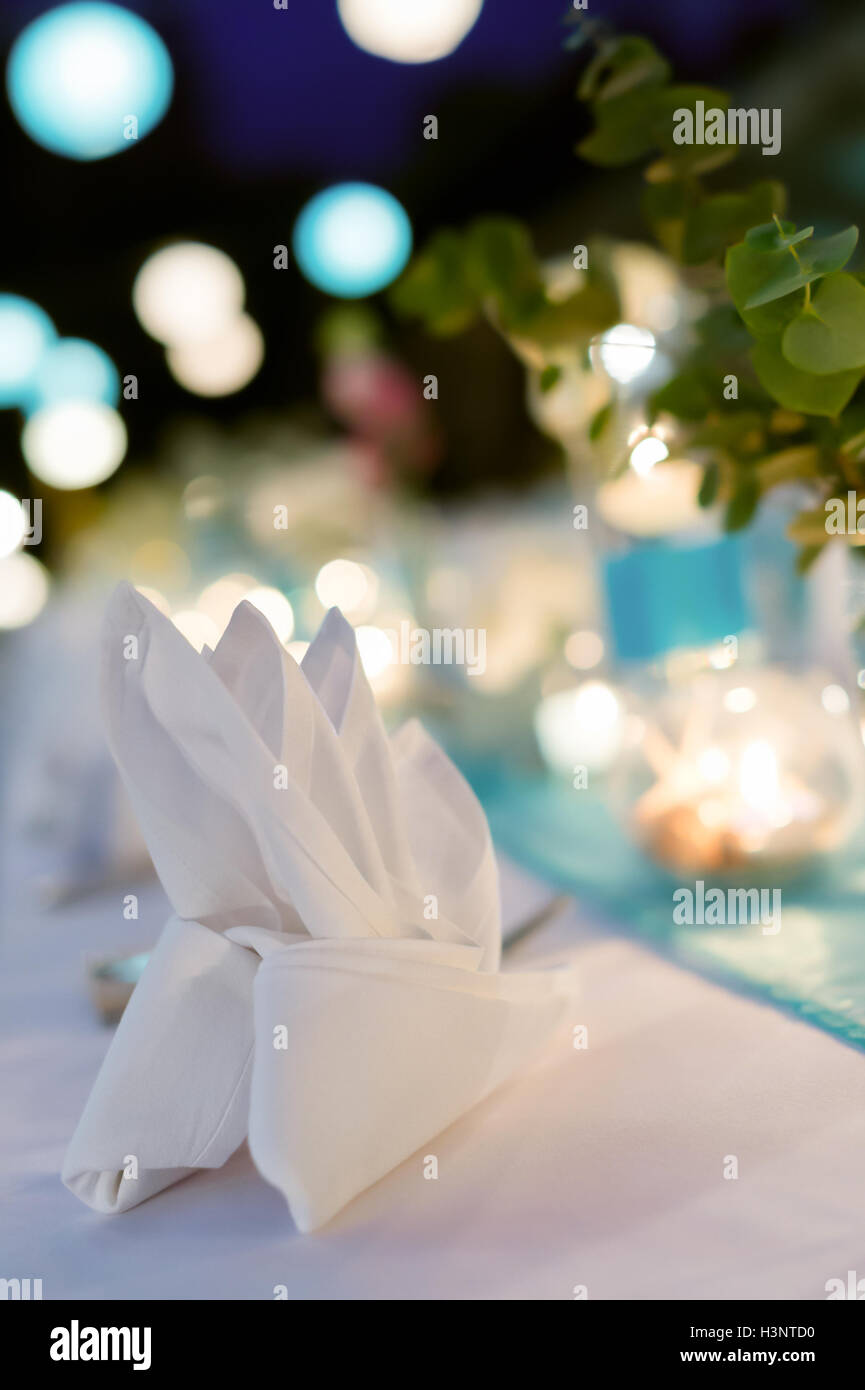 Cena romántica setup, tema blanco y azul decorado con luz de velas, linternas y flores. El enfoque selectivo. Foto de stock