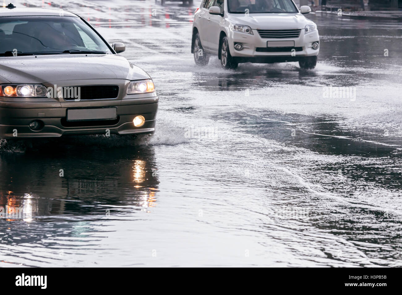 Ciudad camino inundado con agua de lluvia. Automóviles circulando en charcos de agua después del aguacero. Foto de stock