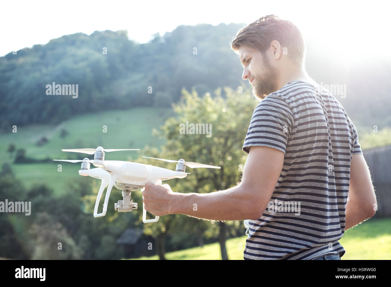 Young hipster hombre sujetando drone. Sunny verde de la naturaleza. Foto de stock