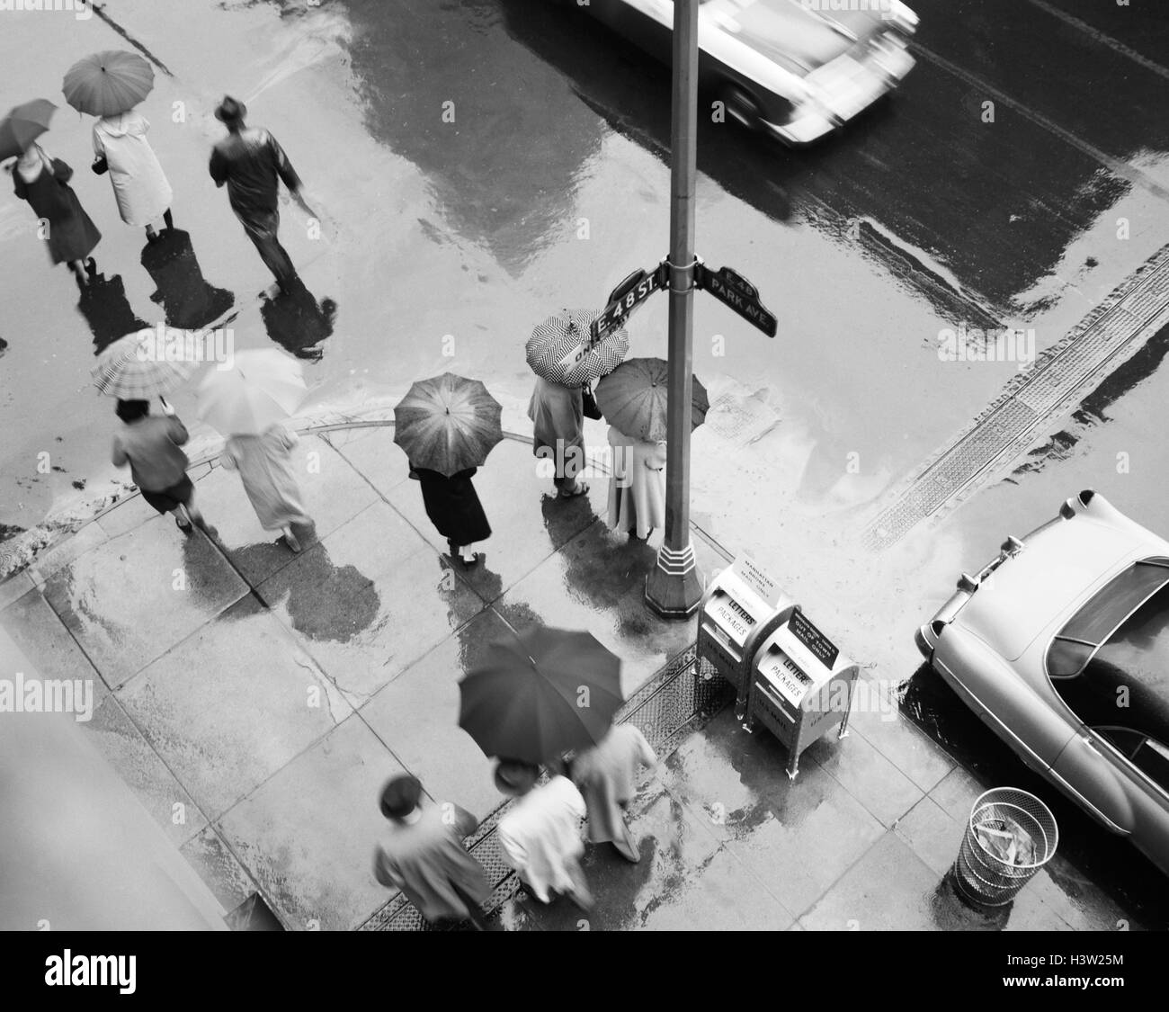 Antena 1950 DE LA ESQUINA DE LA CALLE EN LA LLUVIA peatones con paraguas  coches pavimento mojado PARK AVE & 48TH STREET NUEVA YORK, ESTADOS UNIDOS  Fotografía de stock - Alamy