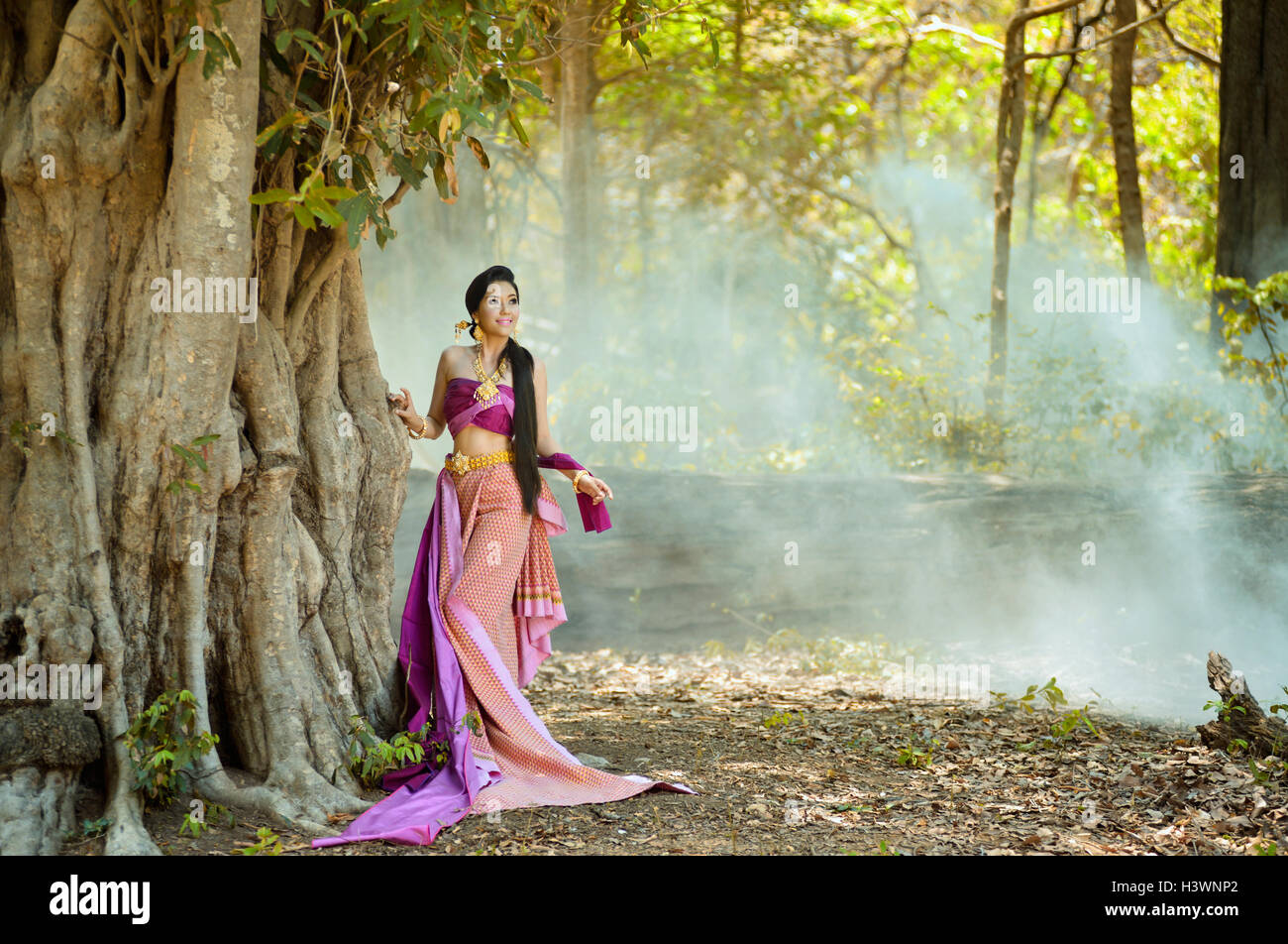 Mujer de pie en el bosque vistiendo ropas tradicionales, Tailandia Foto de stock