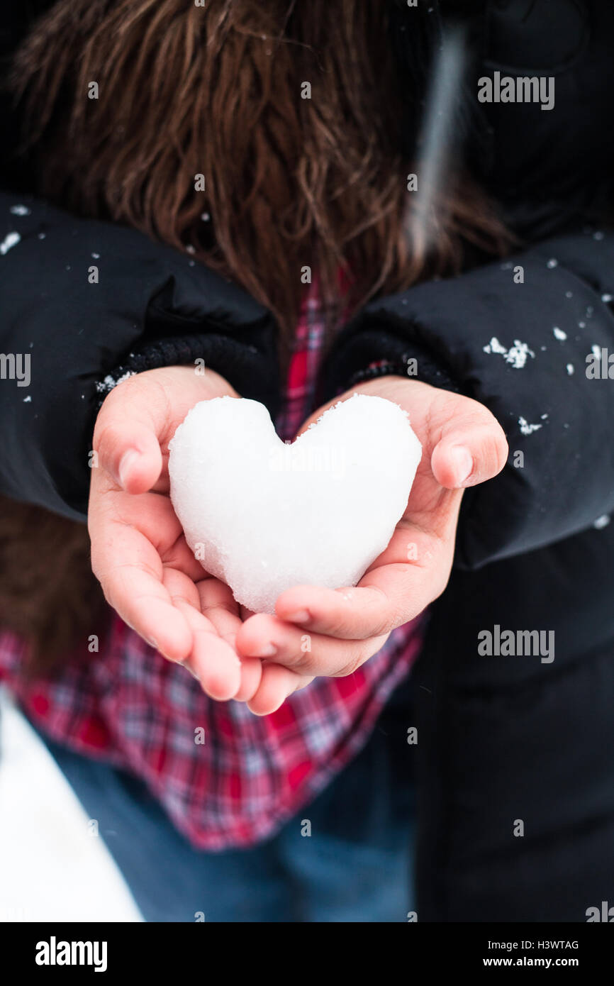 Chica manos sosteniendo la nieve en forma de corazón Fotografía de stock -  Alamy