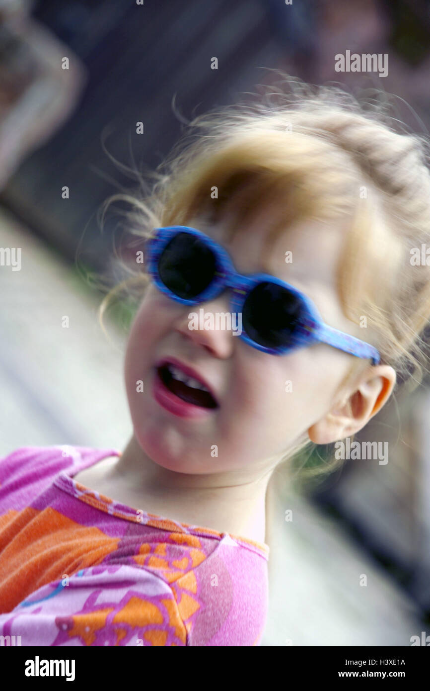Niña de 3 ½ años, gafas de sol, cara, retrato, niño, infancia, verano, fuera, de pelo largo, rubio Rojo, gafas, azul, de expresión, de sorpresas, se sorprende, ver cámara Foto de stock