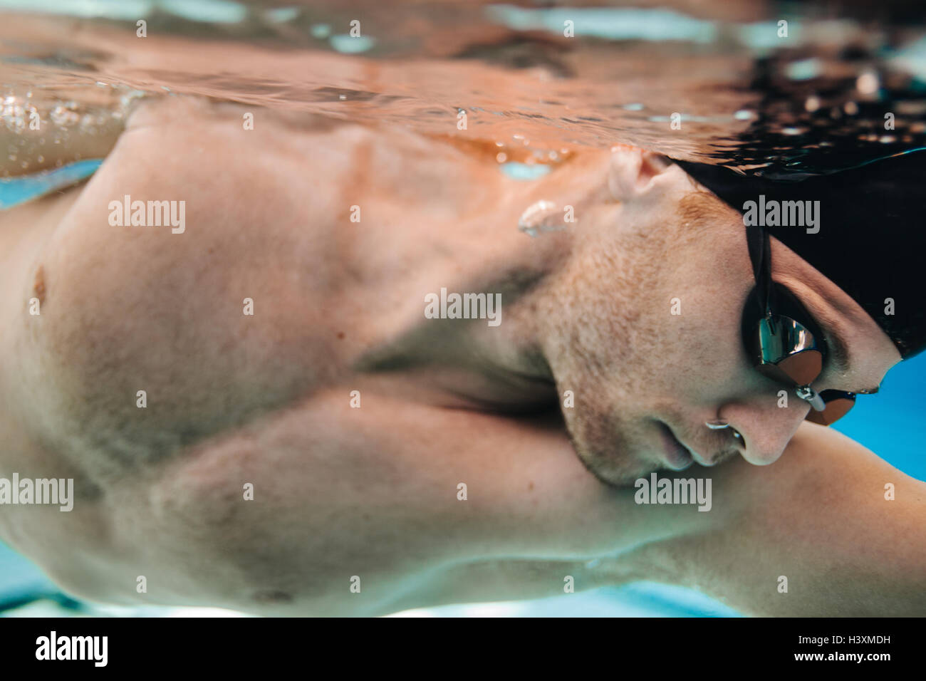 Cerca de filmación subacuática macho joven atleta nadar en piscina Foto de stock