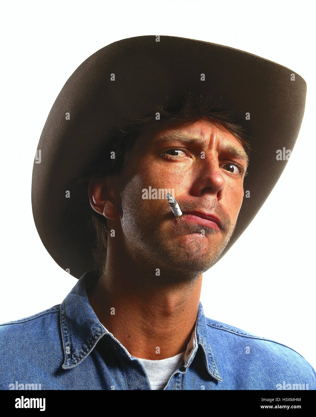 Hombre, STETSON, cigarrillo, retrato, interior, jóvenes, cuidado facial, jugar en serio, ferozmente, el humo, la nicotina, advertir, advertencia, amenaza, amenazar nastily, malicia, con firmeza, determinación, crustily, irritable, crece amargo, studio, recorte Foto de stock
