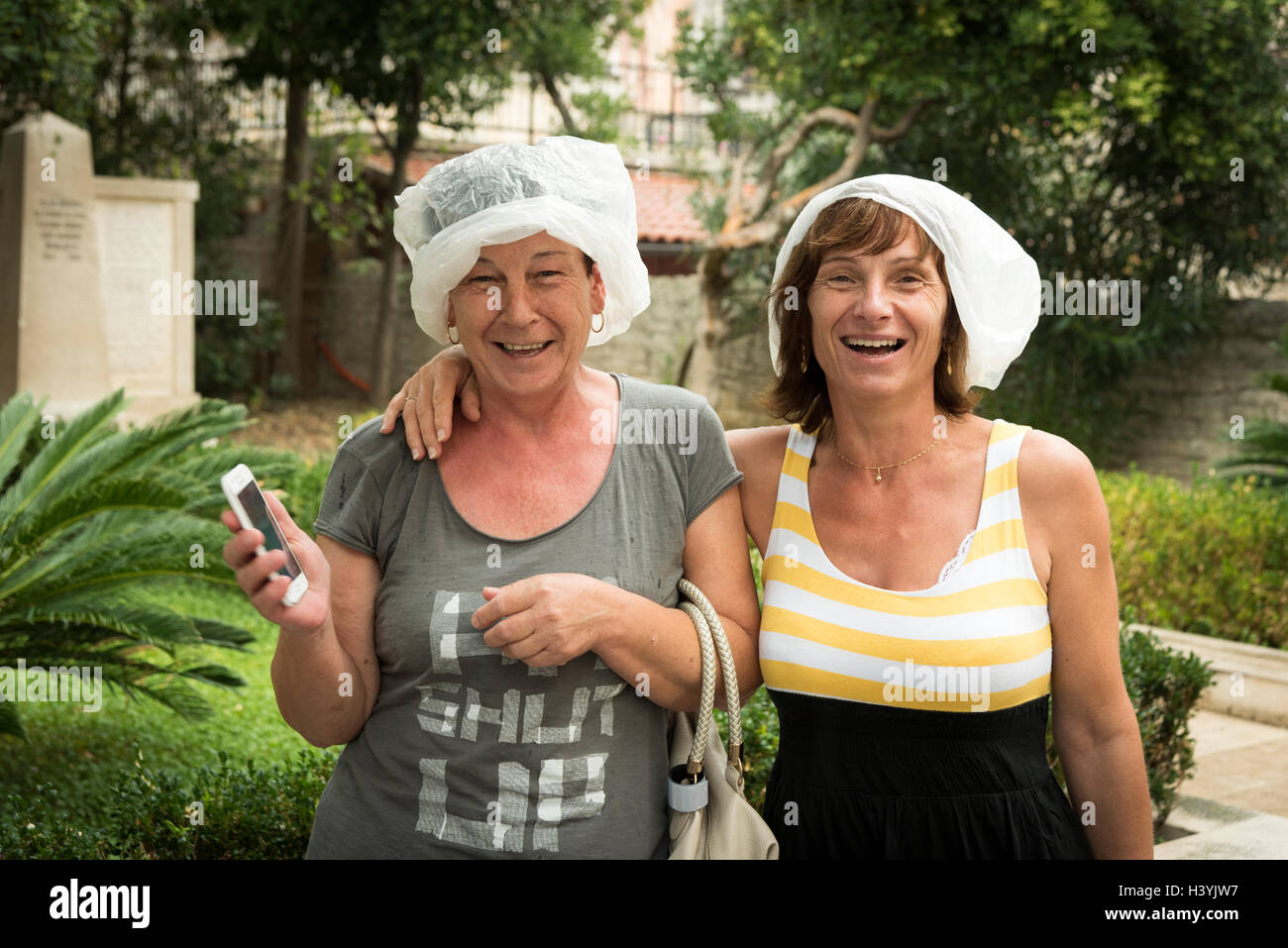 Dos mujeres que llevaban bolsas de plástico en la cabeza para protegerse de  la lluvia en Orebic Croacia durante una ducha de lluvia Fotografía de stock  - Alamy