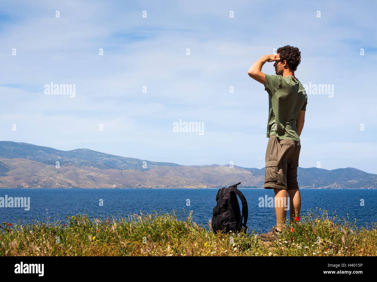 Excursionista con mochila disfrutando de la hermosa vista del mar desde la isla griega de Hydra, copyspace Foto de stock