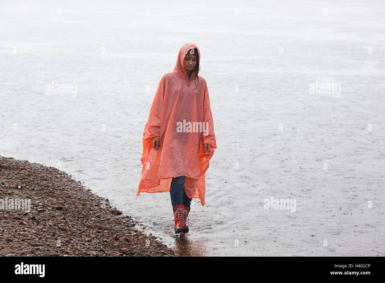 Mujer vistiendo impermeable caminando en Lakeshore en temporada de lluvias Foto de stock