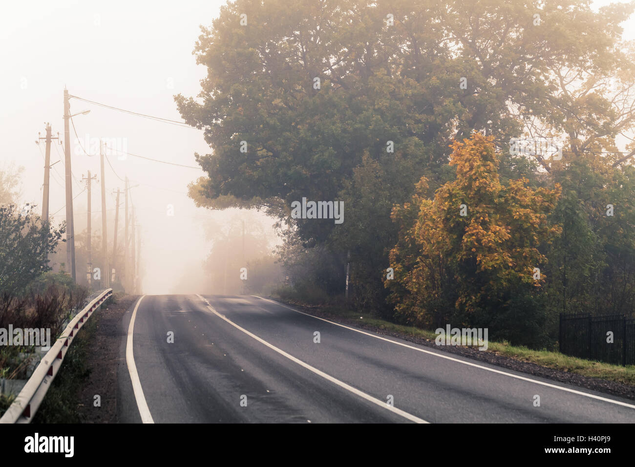 Vacía la autopista rural en otoño de niebla por la mañana y estilizados foto con el efecto de corrección tonal cálida, antiguo filtro estilo instagram Foto de stock