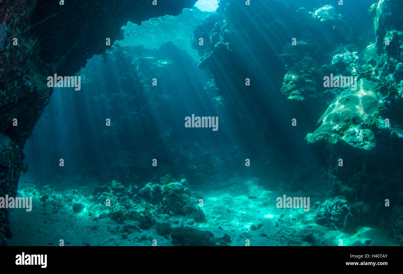 Cueva submarina con rayos de sun streaming a través de la columna de agua. Foto de stock