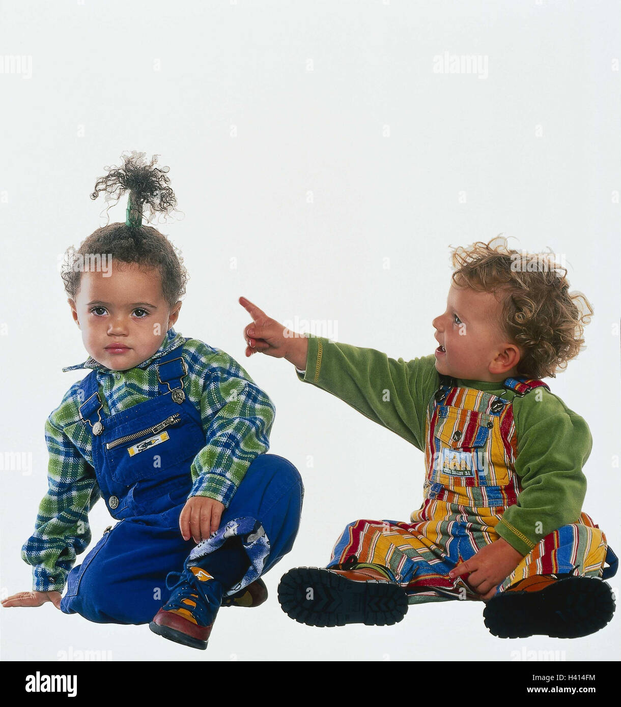 Los bebés pequeños en un mono rojo posando sentada en la nieve Fotografía  de stock - Alamy