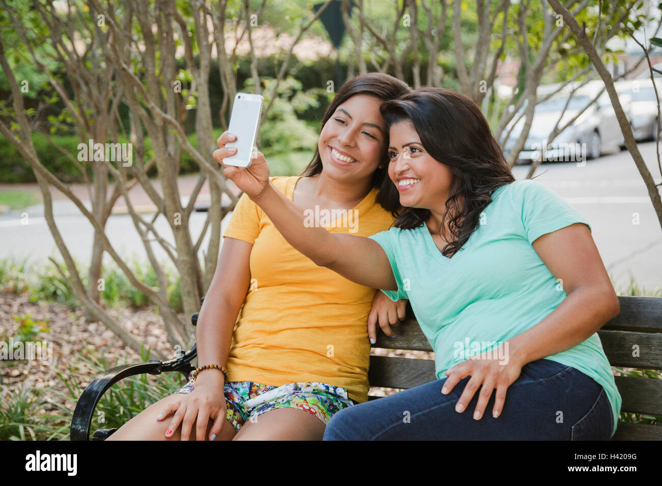 Hispanic madre e hija posando para teléfono celular selfie Foto de stock