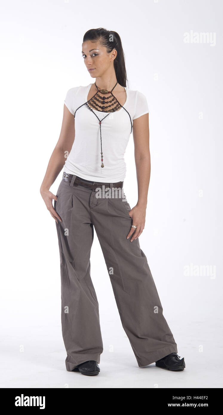Mujer joven, de pie, pantalones marrones, camiseta blanca, collar, studio Foto de stock