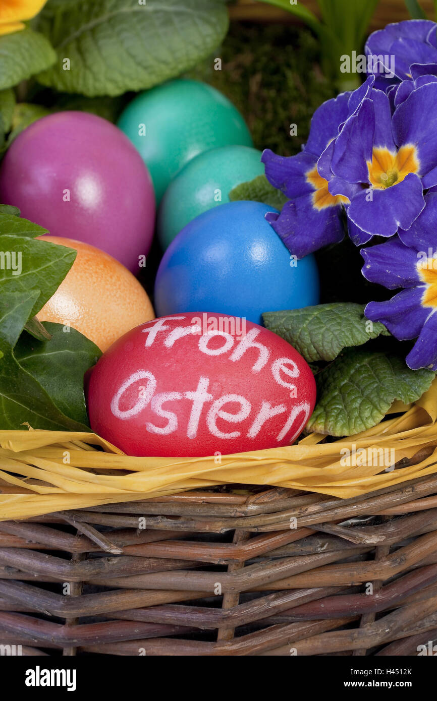 Huevos de Pascua de colores en una canasta con arreglo floral, Foto de stock