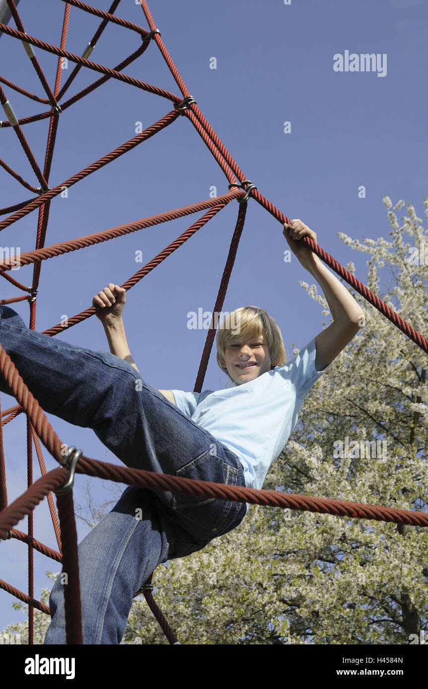 El muchacho, de 12 años, columpios, niño, persona, escalar, stick, cuerdas,  el ocio, la diversión, la alegría, la sonrisa, el equilibrio, el muelle, la  aventura, el parque infantil, el cielo azul Fotografía