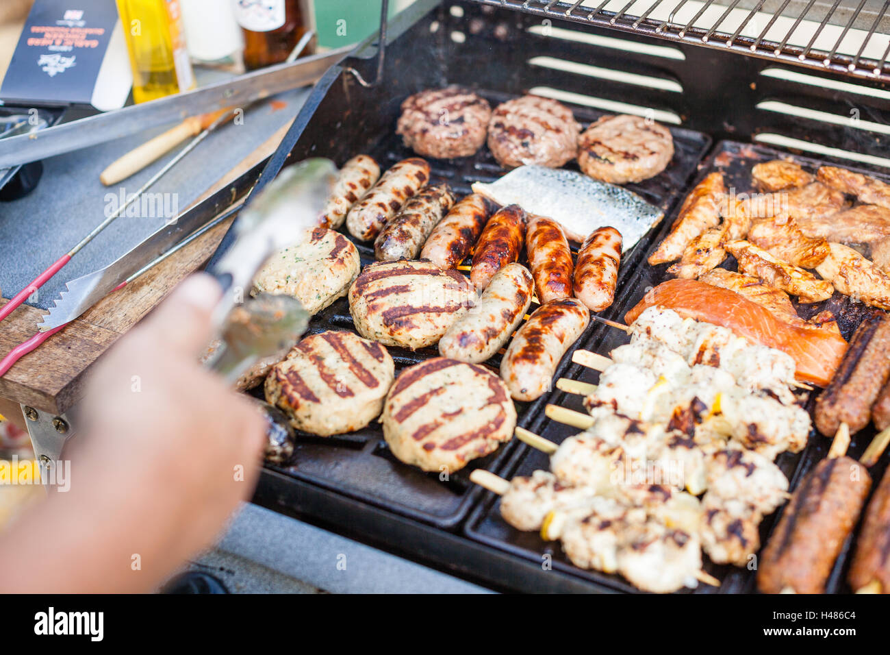 Smokey barbacoa de gas cocinar varias carnes (hamburguesas, salchichas,  pescado, cordero, carnes) en un caluroso día de sol en el jardín de atrás  Fotografía de stock - Alamy