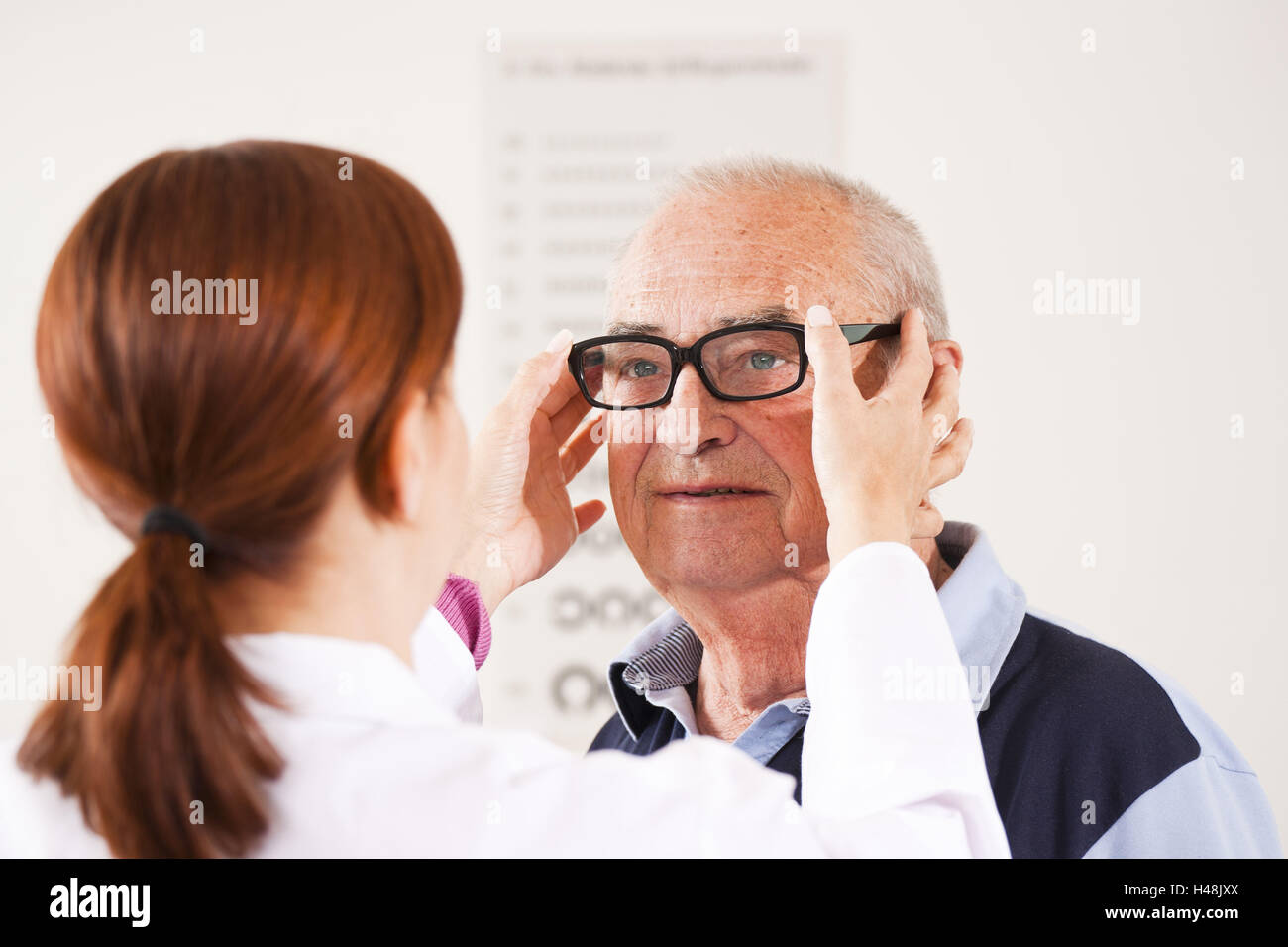 Hombre Senior, oftalmólogo, ajustar las gafas Foto de stock