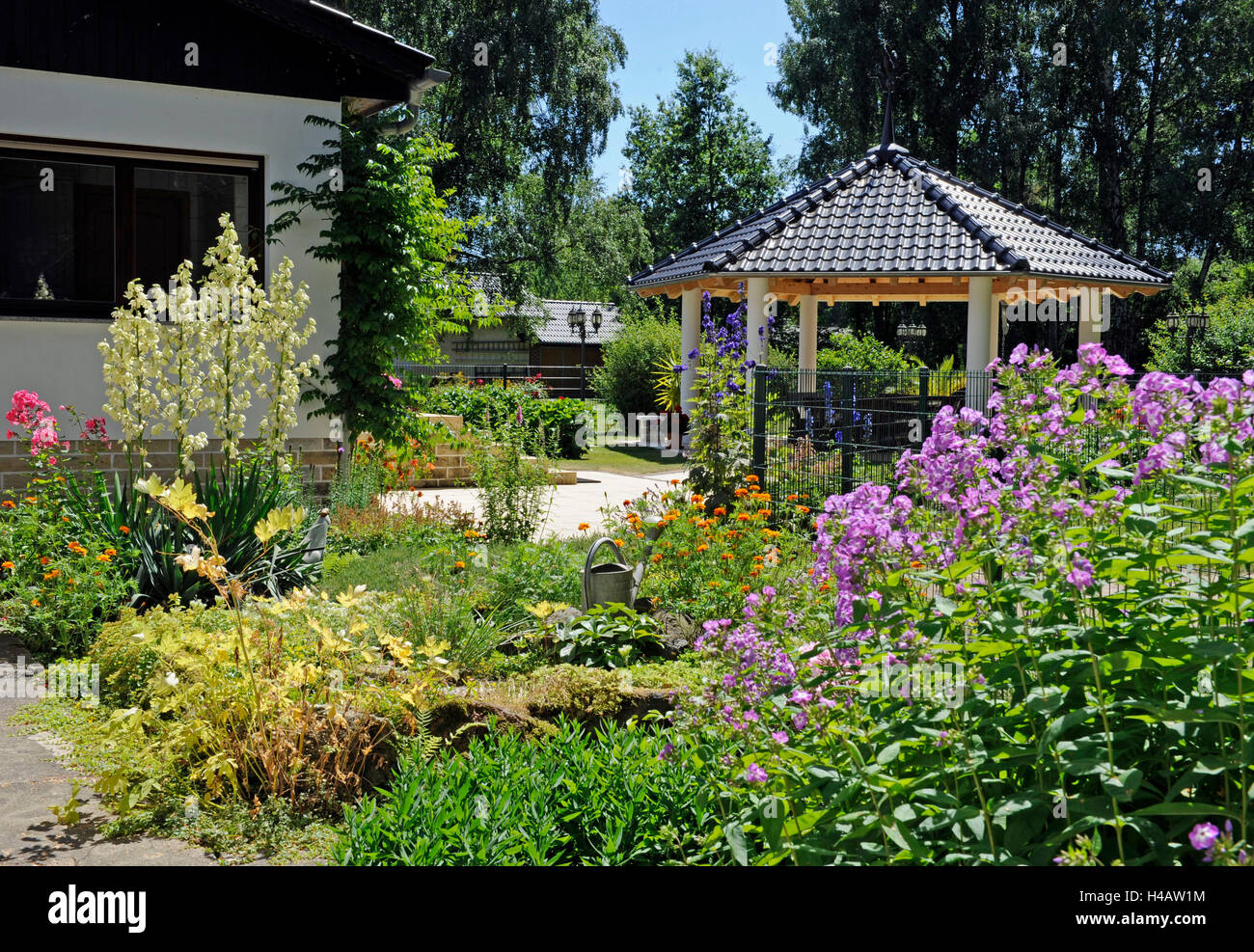Casa jardín con arbustos florecientes, pabellón del jardín en el fondo, Foto de stock