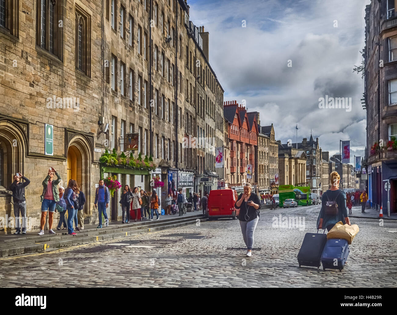 Edimburgo, Escocia - 02 Septiembre 2016 : Mujer jalando maletas de equipaje y turistas en la calle en el casco antiguo de Edimburgo Foto de stock