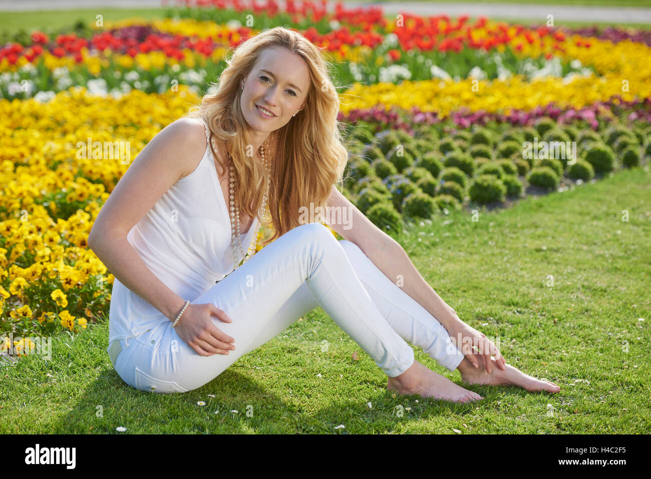 Mujer, jóvenes, pradera, sentado, al parque de la ciudad Foto de stock