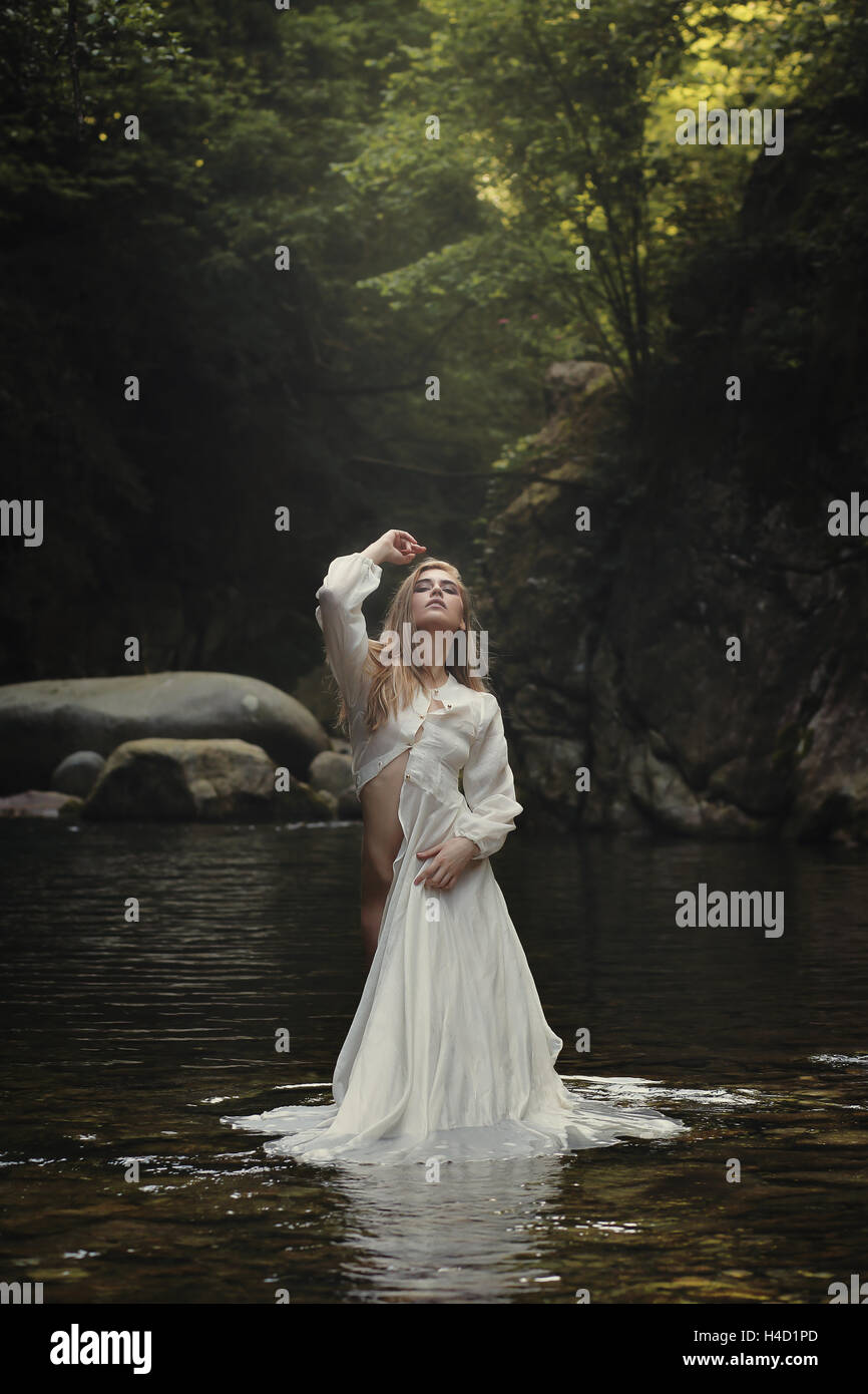 Bella mujer posando en el arroyo de la montaña de ensueño. Y surrealista de fantasía Foto de stock