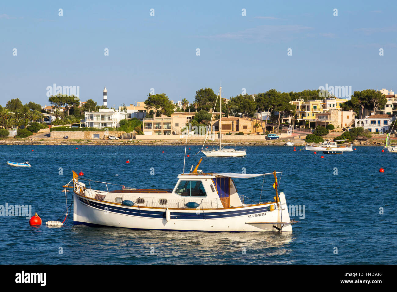 Un barco en el puerto, detrás del faro, Portocolom, en la costa