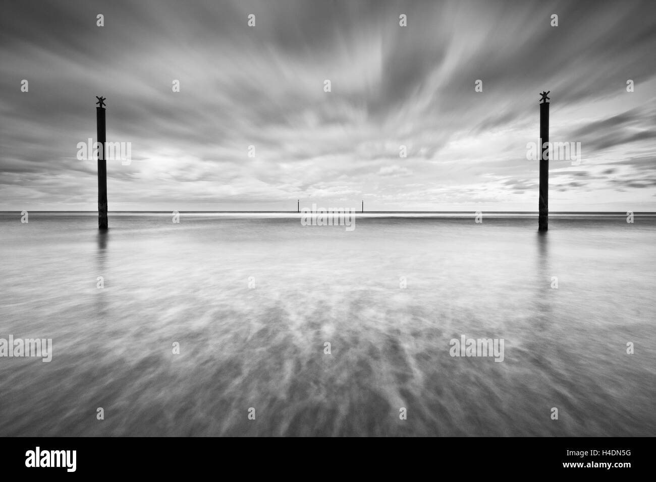 Postes guía de navegación en el Mar del Norte frente a la costa de Northumberland en un día nublado, la larga exposición efecto creativo Foto de stock