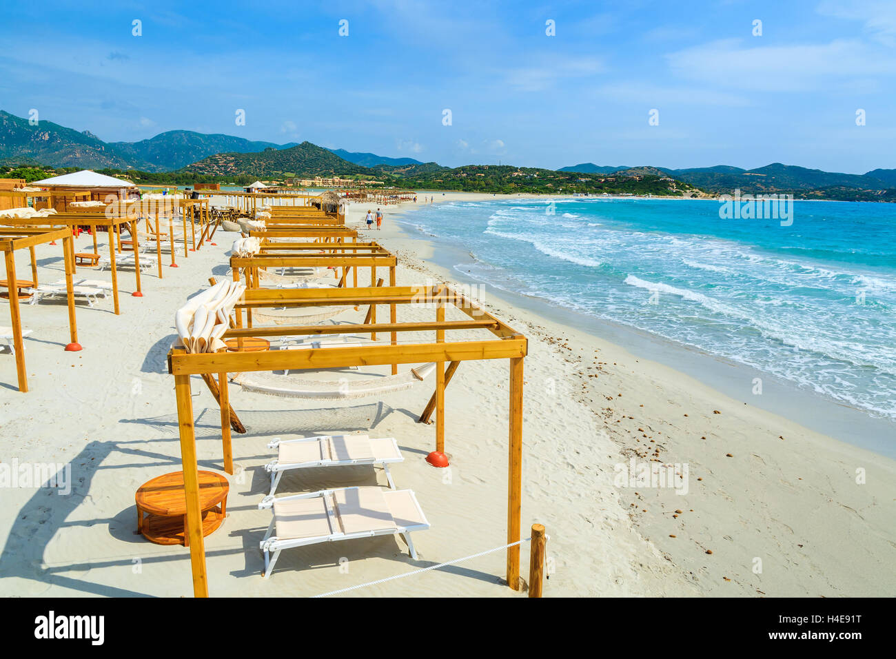 Sillas de madera con la construcción de la sombrilla en la playa de arena blanca en la bahía de Porto Giunco, Cerdeña, Italia Foto de stock