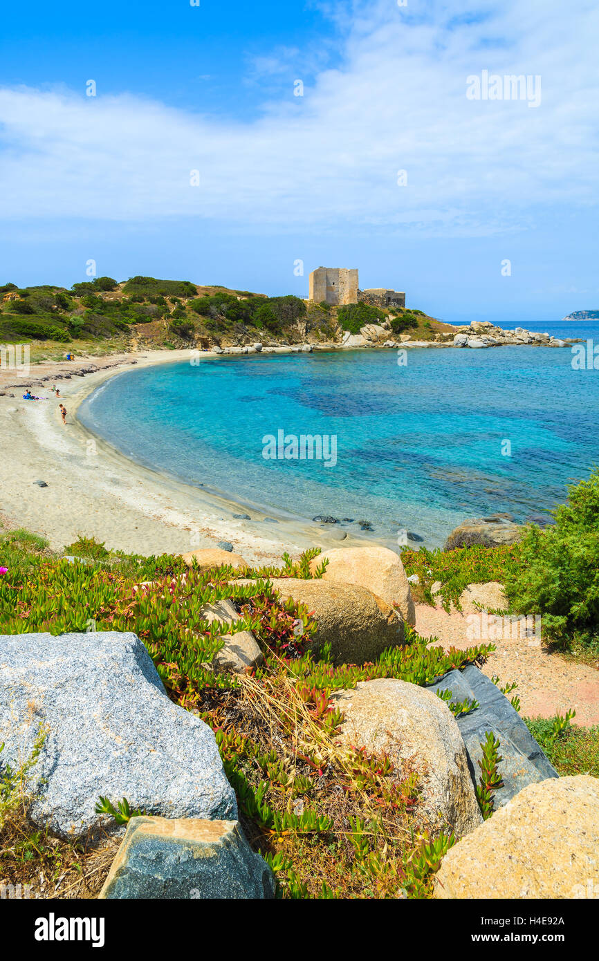 Hermosa bahía con playa y mar azul con castillo en el fondo cerca de Porto Giunco, puerto de la isla de Cerdeña, Italia Foto de stock