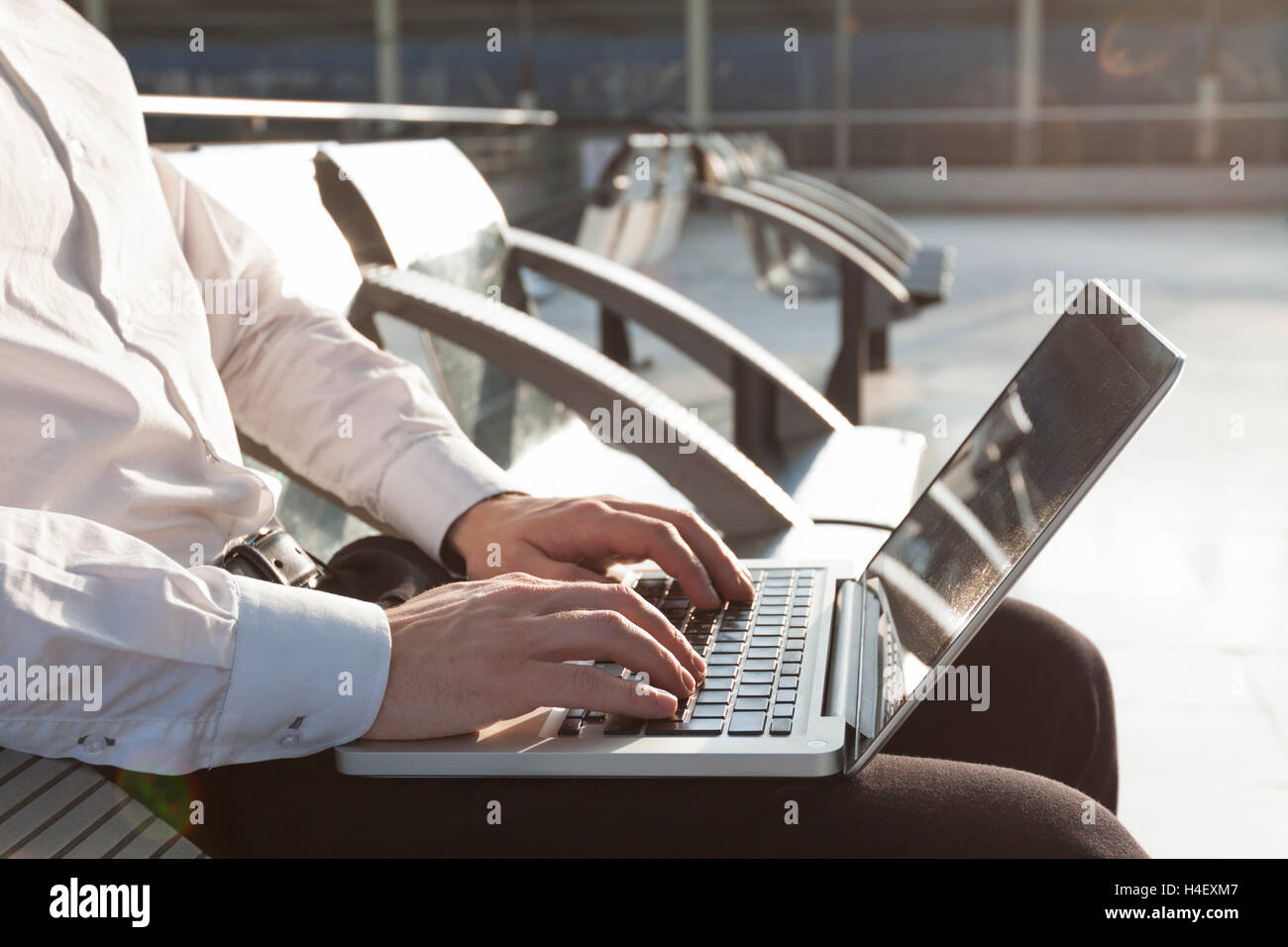 El empresario en la sala de espera del aeropuerto escribiendo en el ordenador portátil Foto de stock