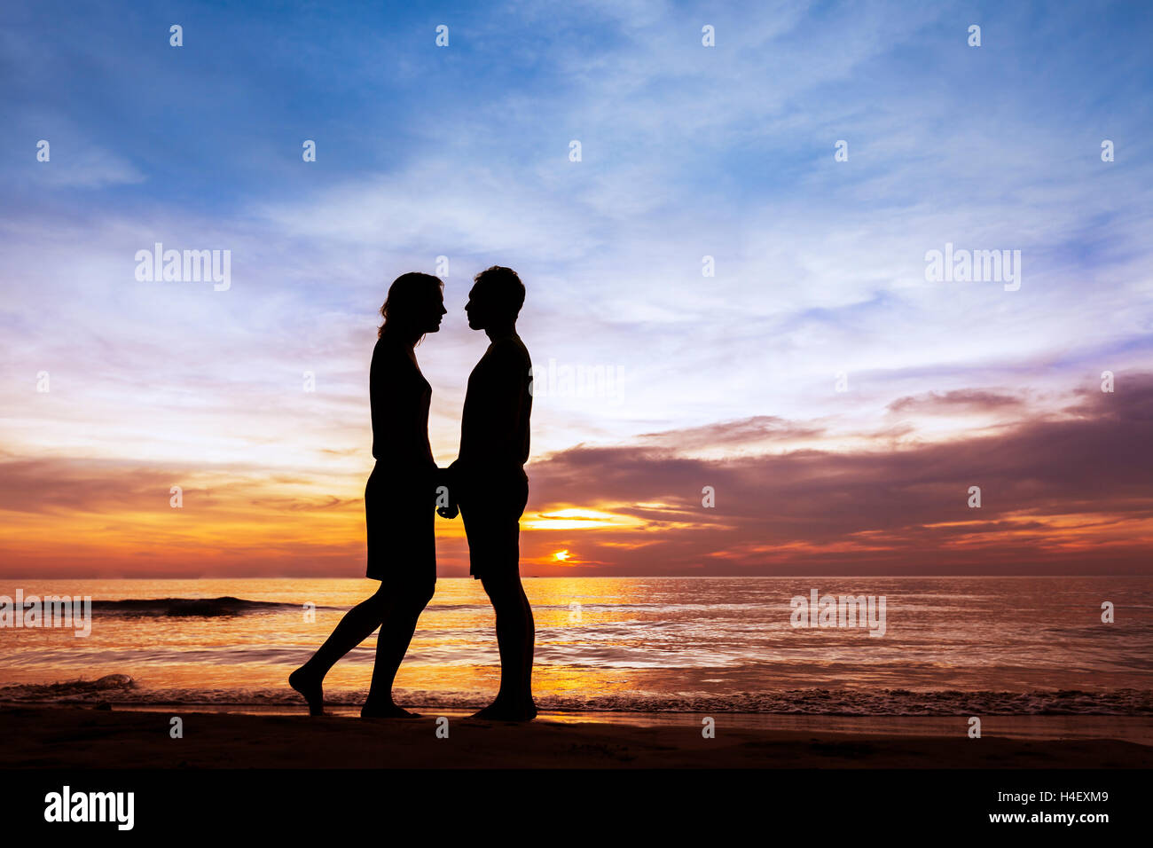 Pareja besándose en la playa con un hermoso atardecer en el fondo Foto de stock