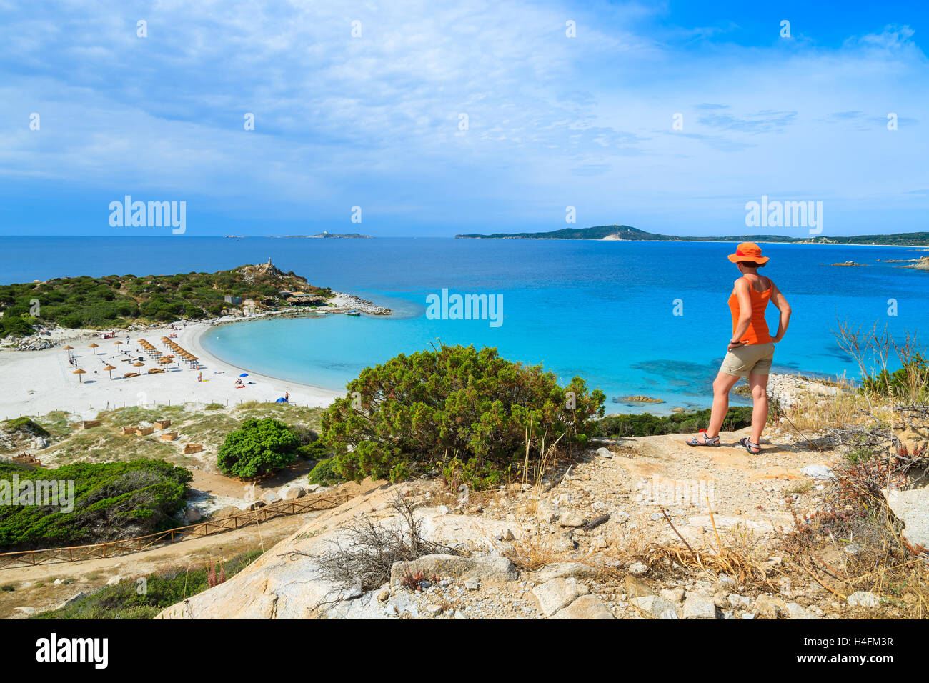 Joven turista de pie en alto vasija de barro con vista de la hermosa bahía con playa de arena en Punta Molentis, Cerdeña, Italia Foto de stock