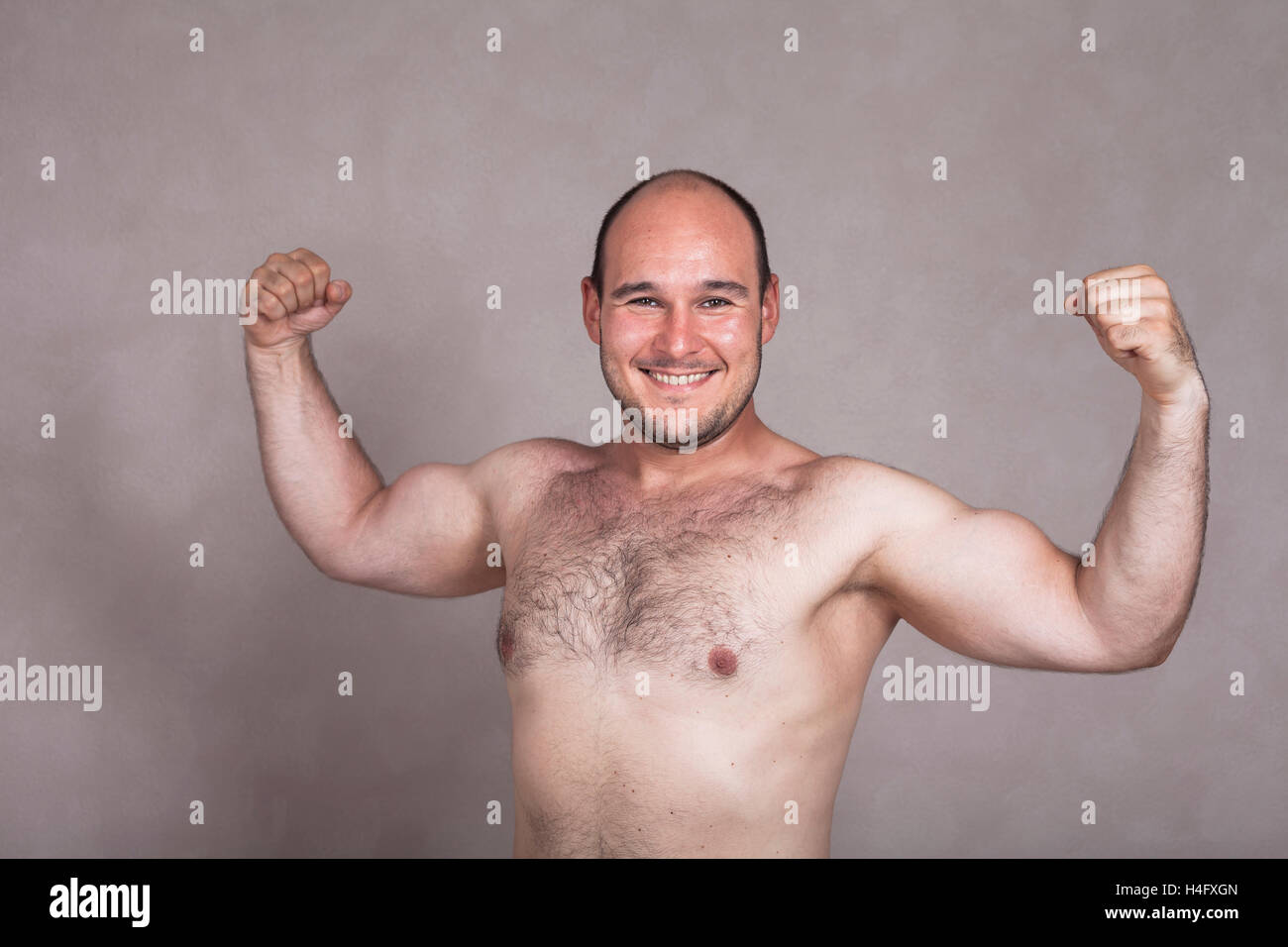 Retrato del hombre descamisado feliz posando y mostrando sus brazos fuertes y peludo cuerpo. Foto de stock