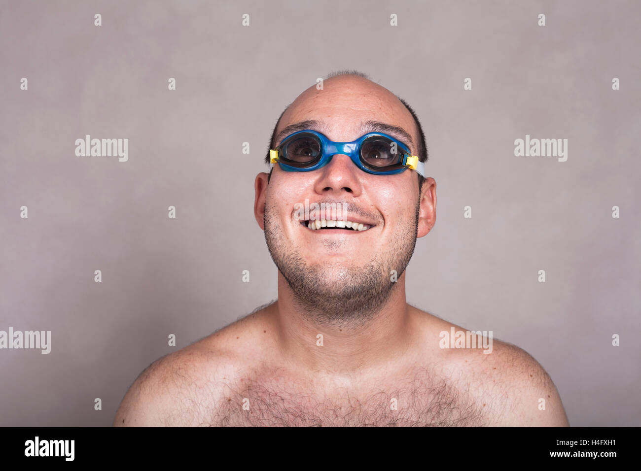 Primer plano de gracioso hombre desnudo en gafas de natación soñar despierto y mirando hacia arriba. Foto de stock