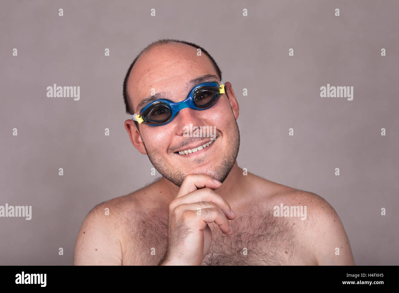 Primer plano de gracioso hombre desnudo en gafas de natación soñar despierto y mirando hacia usted. Foto de stock