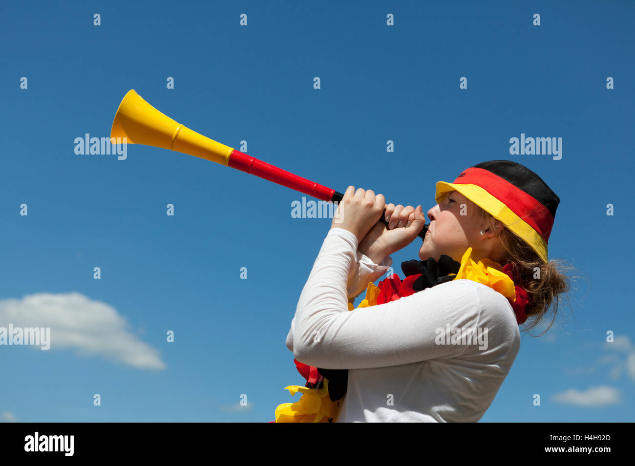 Mujer joven soplando en una vuvuzela, negro oro rojo, la Copa Mundial de la fifa 2010 Foto de stock