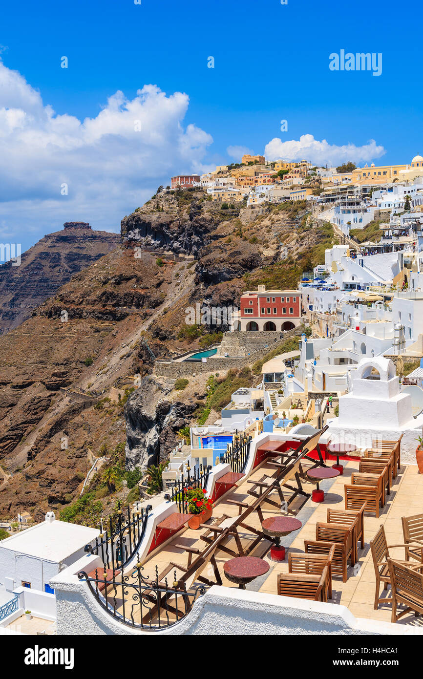 Sillas en la terraza y una hermosa vista de la aldea sobre el acantilado de Firostefani, isla de Santorini, Grecia Foto de stock