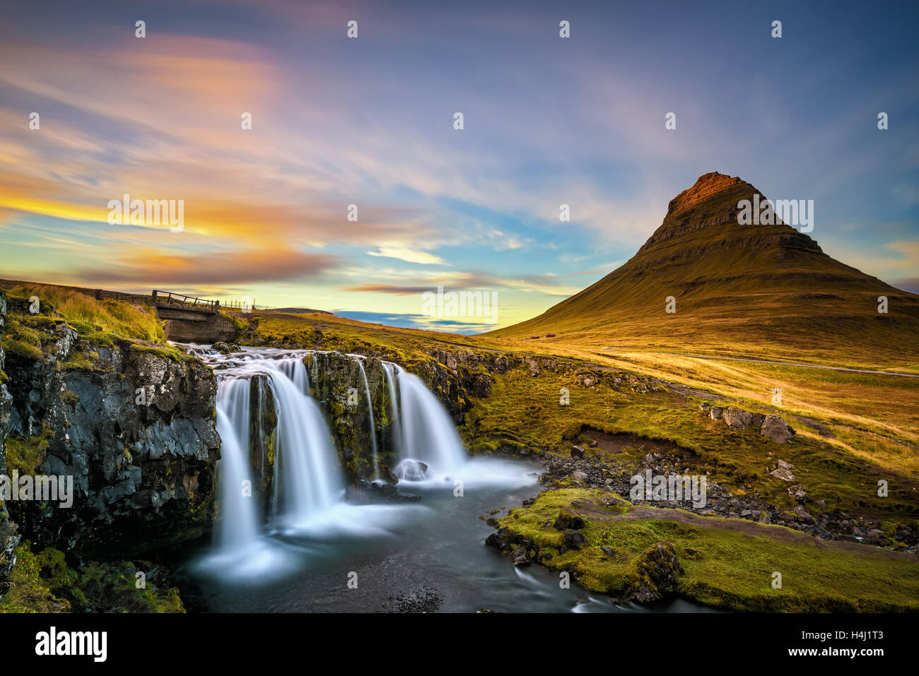 Verano atardecer en la famosa montaña Kirkjufell Kirkjufellsfoss cascada con en el fondo en Islandia. La larga exposición. Foto de stock