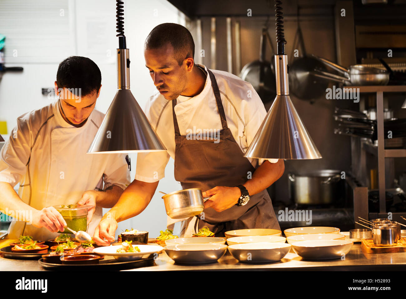 Dos chefs en la cocina de un restaurante, chapado de alimentos. Foto de stock