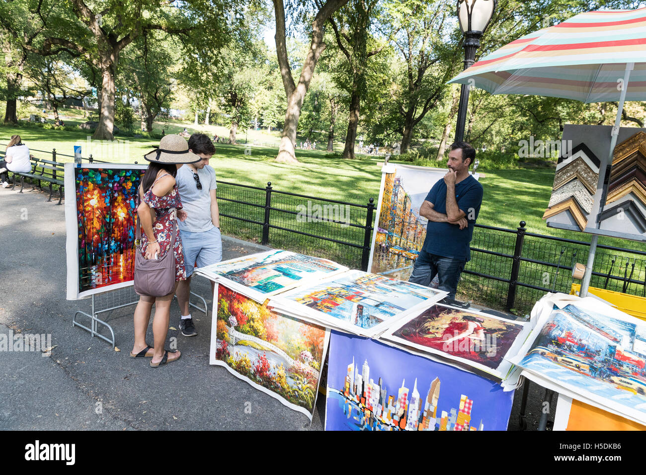 Vendedores ambulantes vendiendo arte / lienzos / pinturas a pareja joven en el Parque Central de la ciudad de Nueva York Foto de stock