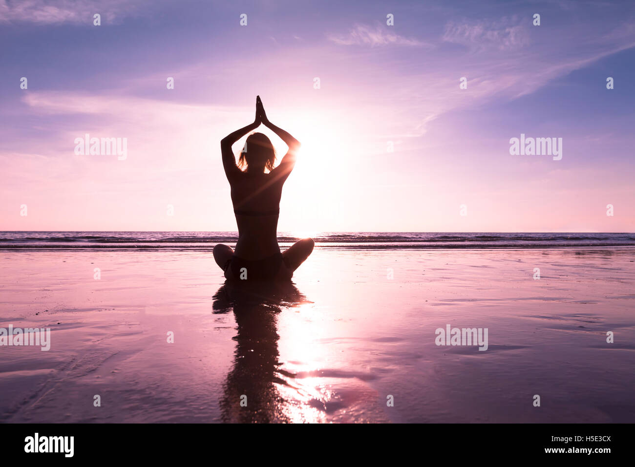 Hembra mañana practicando ejercicios de yoga en la playa para la curación Foto de stock