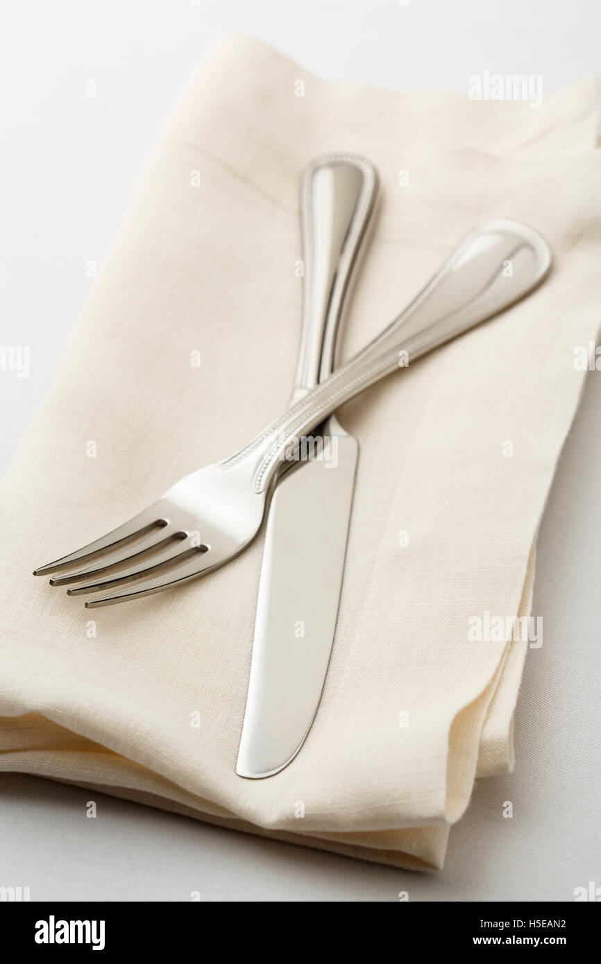 Simple, clásico lugar para poner la mesa con cubertería de plata de alta calidad tenedor y cuchillo en una servilleta de lino blanco. Foto de stock