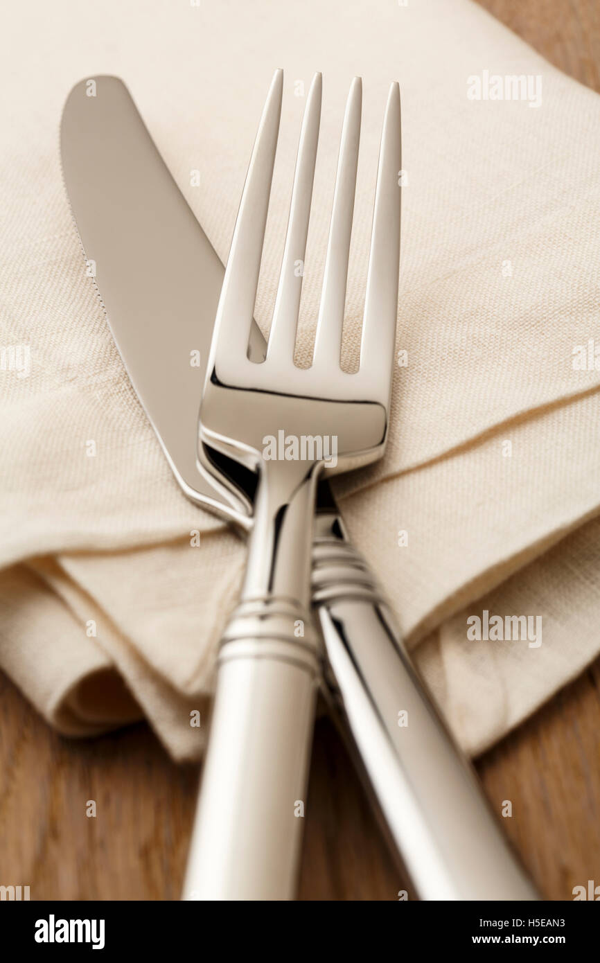 Simple, clásico lugar para poner la mesa con cubertería de plata de alta calidad tenedor y cuchillo en una servilleta de lino blanco. Foto de stock