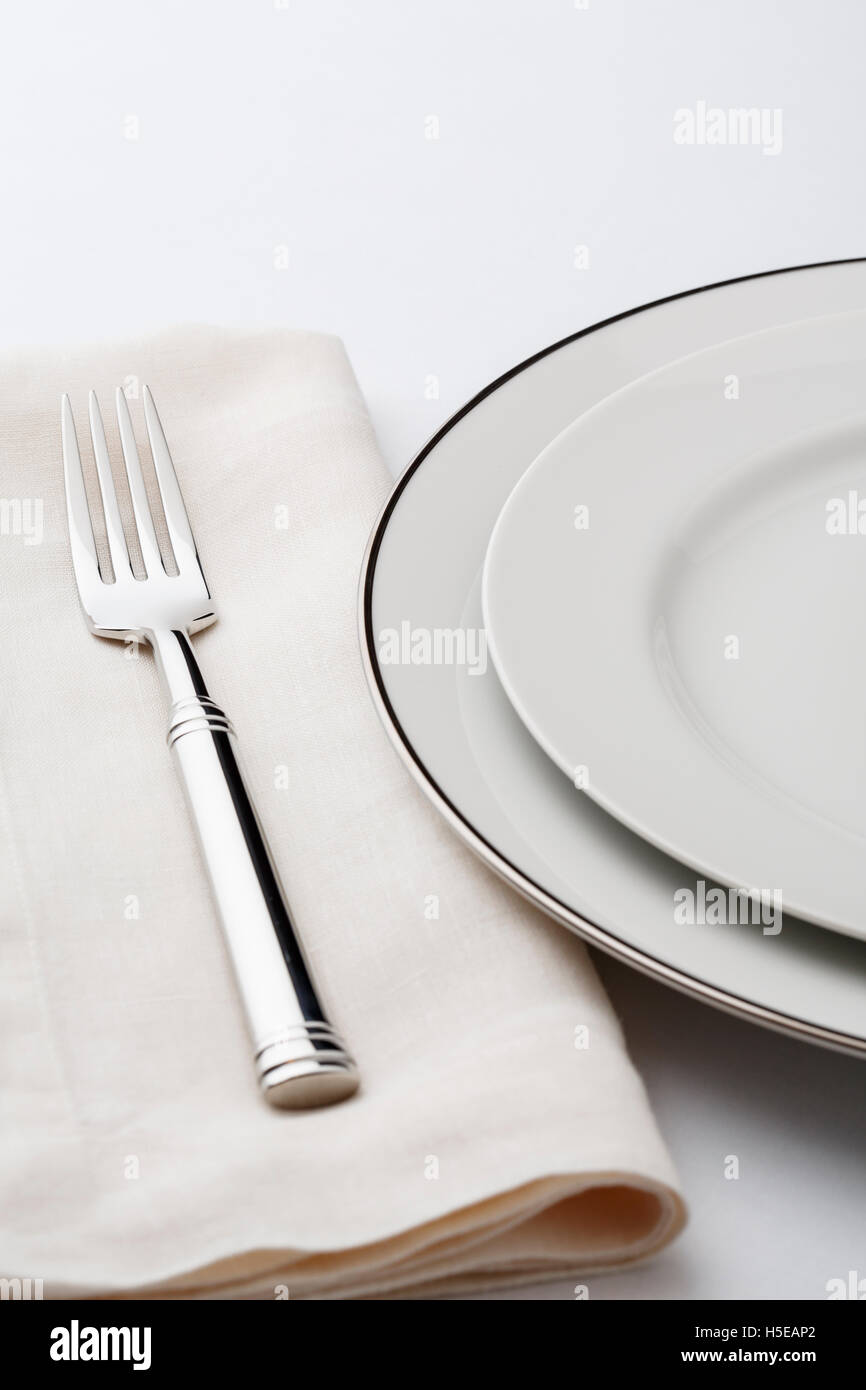 Mesa de comedor fino ajuste place setting con alta calidad estilo clásico blanco, vajilla y cubertería de plata de la servilleta de lino horquilla. Foto de stock